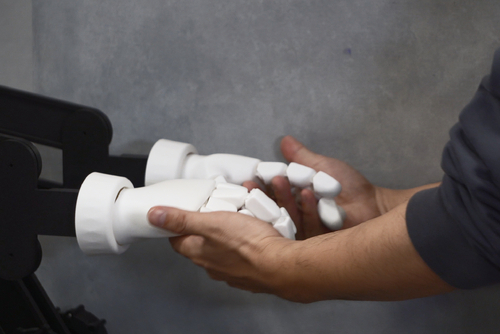 Image of robot and human hands connecting from “Shall We Dance? Resonance of Intentions with an Embodied Agent based on the Free Energy Principle”